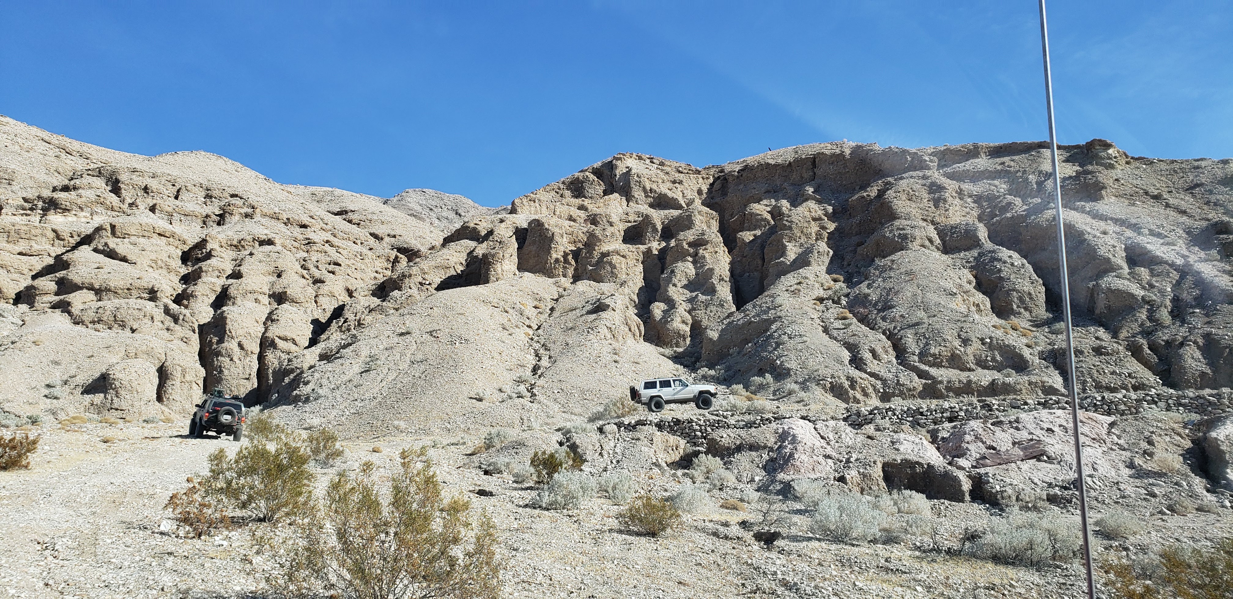 A green XJ and a white XJ staged in front of rock formations.